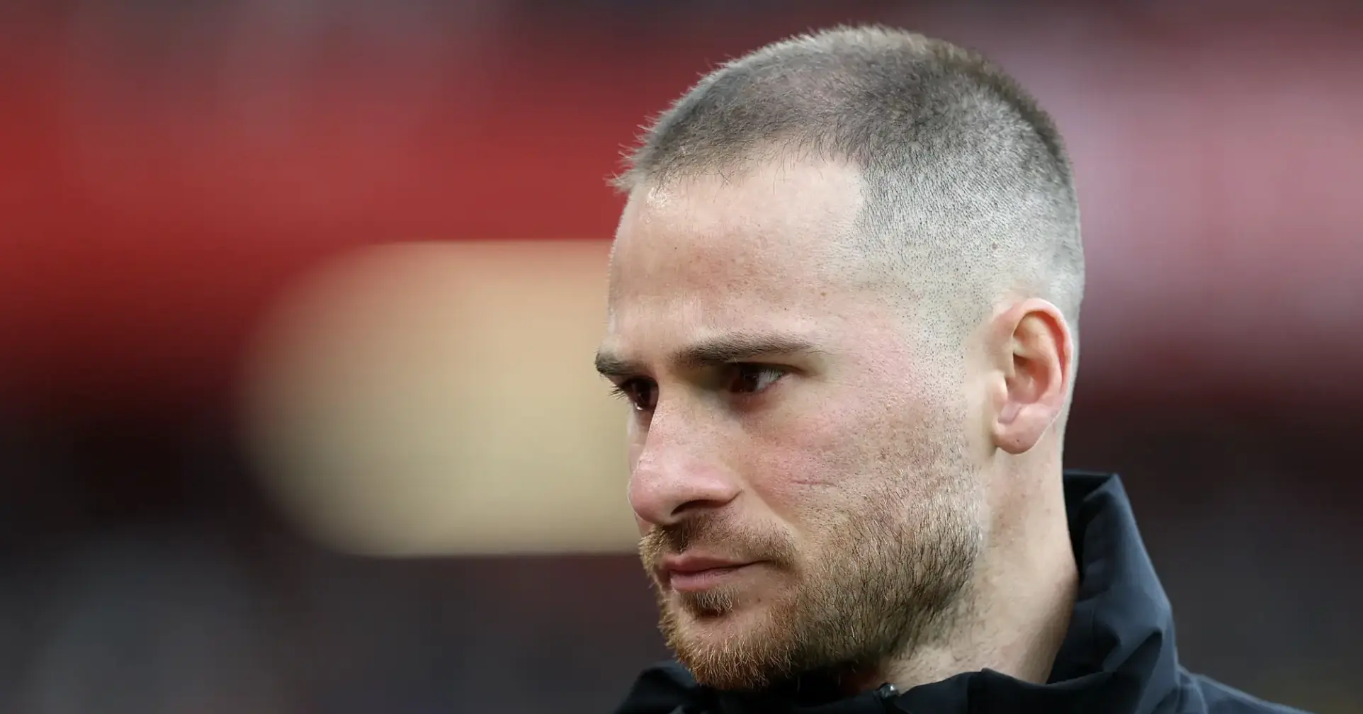 Close-up profile of a man with a fade haircut and beard, looking to the left.