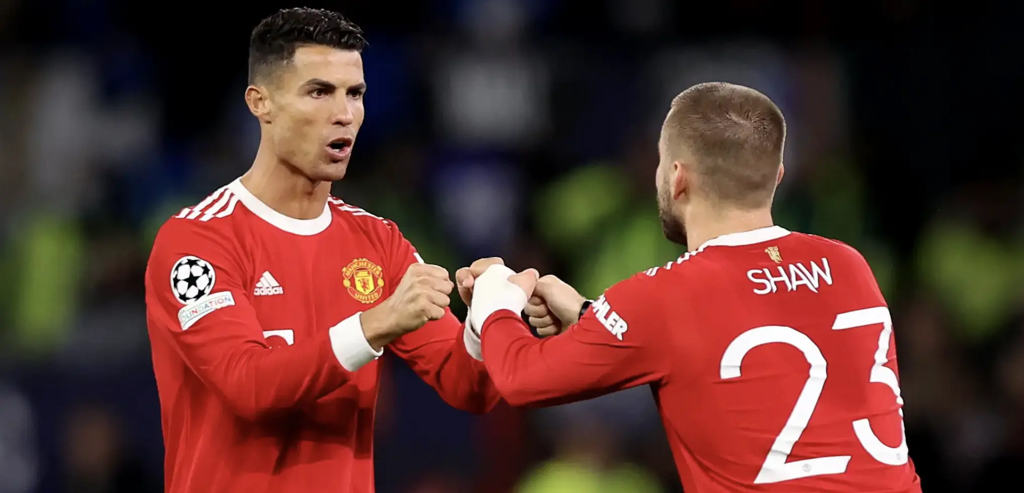 Two Manchester United teammates celebrate with a fist bump on the pitch during a Champions League match.