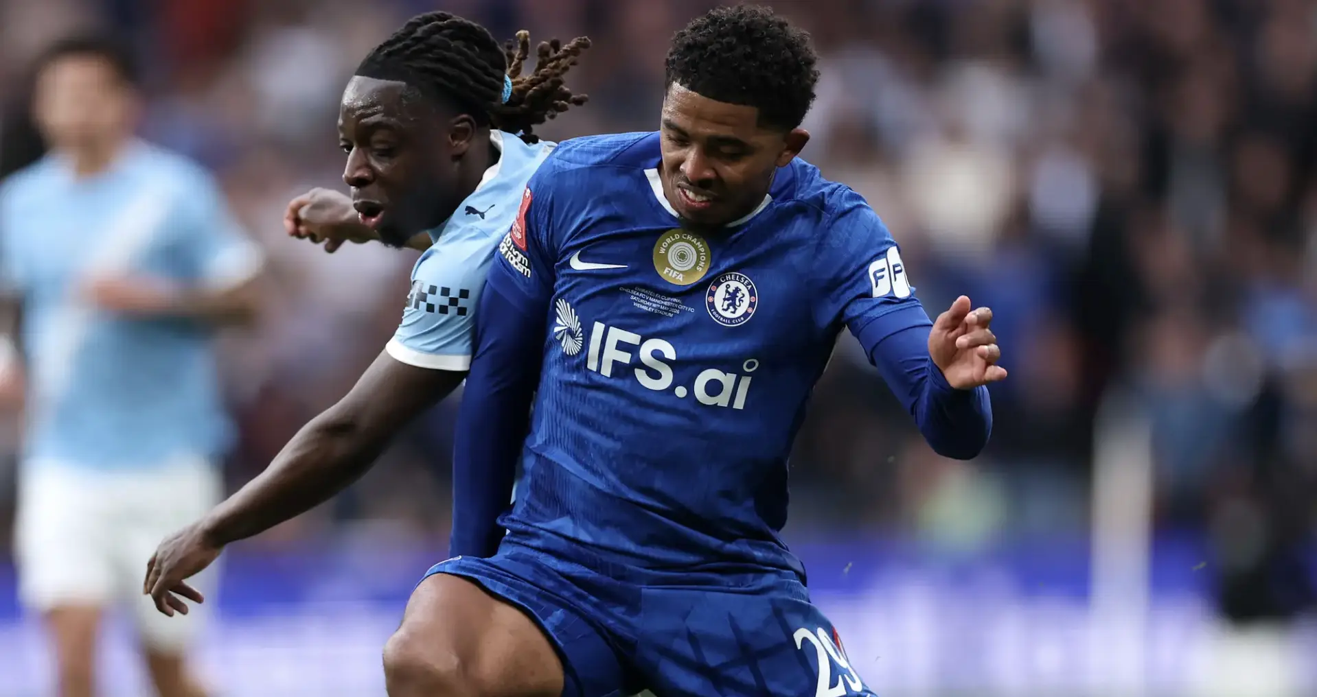 Chelsea FC player in blue foreground contesting the ball with an opposing player in light blue on a crowded pitch in motion