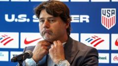 Man in a suit at a press conference, adjusting his tie, with U.S. Soccer logos in the background.