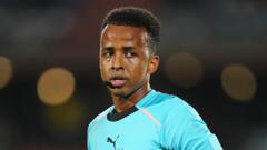 cover-7675-1780986888jpg - 實發體育 Close-up of a man wearing a turquoise sports jersey on a stadium field, looking at the camera.