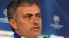 Close-up of a man with gray hair speaking at a press conference, blue backdrop with Champions League logos.