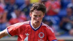 Soccer player in a red jersey on the field during a match, focused on the play.