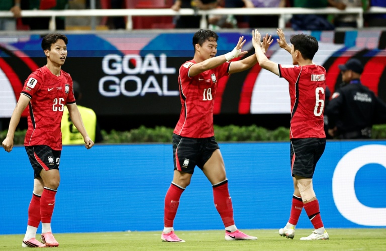 cover-7792-1781238888jpg - 實發體育 Three soccer players in red jerseys celebrate a goal, high-fiving on the field with fans in the stands behind them.