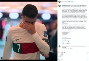 xESxyi7ot3lAzcYk6UK0fnRfTHFcB_cY5F8Xs-RfF7M - 實發體育 Young male soccer player in a white jersey with red and green stripe covering his face with his right hand, looking distressed in a blurred indoor stadium background.