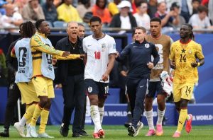 England forward no. 10 Rooney walks off the pitch with coaches and Brazil players in yellow nearby during a 2006 FIFA World Cup match.