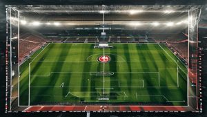 cover-8770-1784250032jpg - 實發體育 Aerial view of a soccer stadium at night with a well-manicured green pitch and bright floodlights overhead.