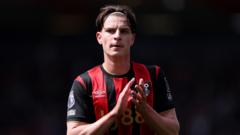 Soccer player in a red and black striped jersey clapping on the pitch during a match.