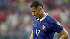 Professional footballer in a blue France kit with number 17, standing on the pitch with a blurred crowd behind.