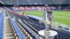 cover-9204-1786492859jpg - 實發體育 Shiny trophy on a pedestal beside blue stadium seats in an empty football stadium.