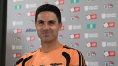 Smiling man in an orange jersey posing for a photo against a sponsorship backdrop.
