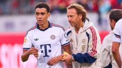 Two soccer players in white jerseys walk on the field during a match, with a blurred crowd in the background.