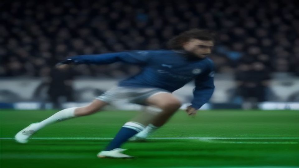 Soccer player in a blue jersey sprinting on a green field, motion blur behind him.