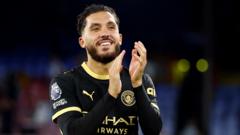 cover-9392-1787961657jpg - 實發體育 Soccer player in a black jersey clapping on the pitch at night stadium lights in the background