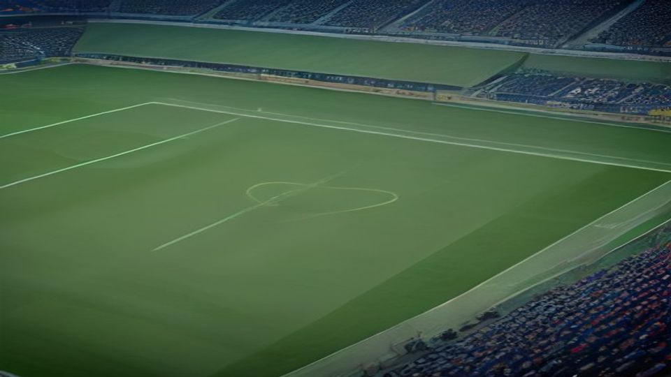 Empty football stadium with a green pitch and surrounding blue seating, no players visible.